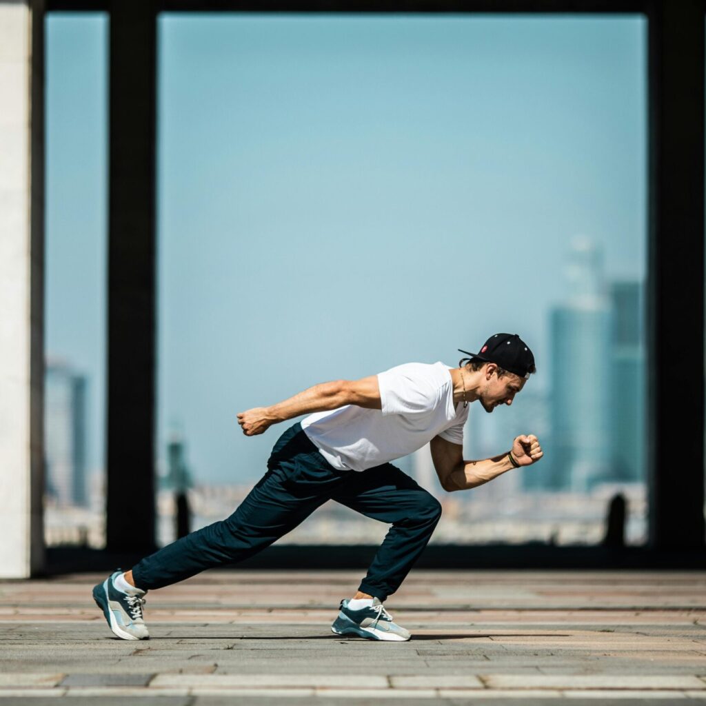 Dynamic shot of a young man sprinting outdoors in an urban setting with skyscrapers in the background.